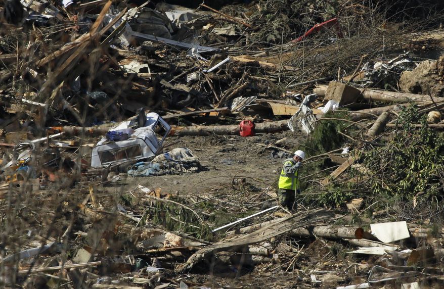 A search worker walks near a camper shell at left as he walks through debris Tuesday, April 1, 2014, near Darrington, Wash., at the site of the deadly mudslide that hit the community of Oso,Wash. on March 22, 2014. (AP Photo/Ted S. Warren)
