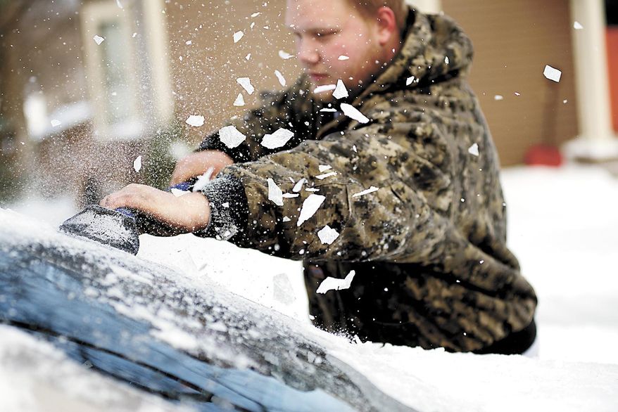 Brandon Kalenda scrapes ice off the back window of his car, Tuesday, April 1, 2014, in Fergus Falls, Minn. A spring blizzard that dumped heavy amounts of snow in parts of the Upper Midwest on Monday. (AP Photo/The Fergus Falls Daily Journal, Rian Bosse)