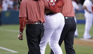 In this March 31, 2014 photo, Los Angeles Angels hitting coach Don Baylor is helped off the field after he broke his right leg while catching Vladimir Guerrero&#39;s ceremonial first pitch before the Angels&#39; opening day baseball game with the Seattle Mariners, in Anaheim, Calif. (AP Photo/Jae C. Hong)