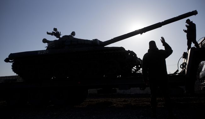 Russian officers gesticulate to the driver of Russian tank T-72B at the Ostryakovo railway station not far from Simferopol, Crimea, Monday, March 31, 2014. Russian tanks T-72B will be stationed on former Ukrainian military bases. (AP Photo/Pavel Golovkin)