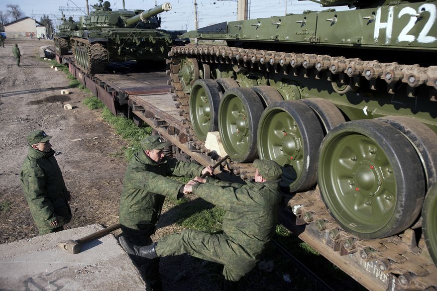 Russian solders prepare to move a Russian tank T-72B at the Ostryakovo railway station not far from Simferopol, Crimea, Monday, March 31, 2014. Russian tanks T-72B will be stationed on former Ukrainian military bases. (AP Photo/Pavel Golovkin)
