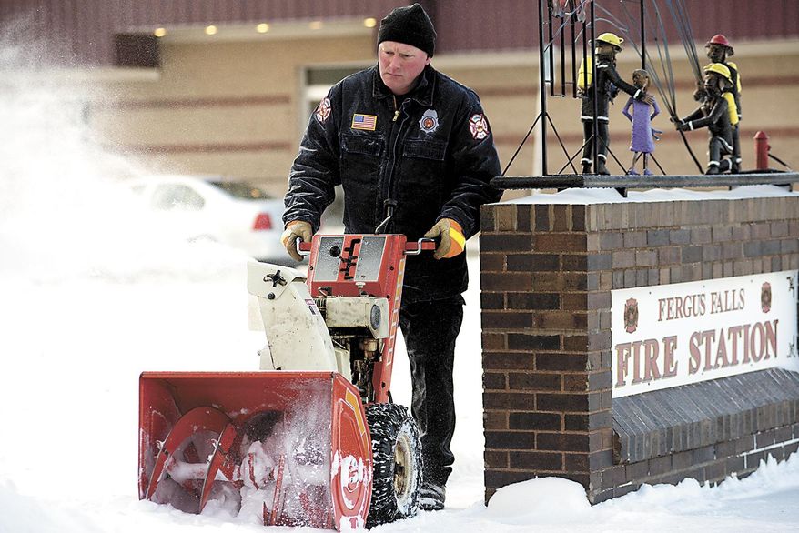 Craig Hebert blows snow from the front walk of the Fergus Falls fire station, Tuesday, April 1, 2014, in Fergus Falls, Minn. A spring blizzard that dumped heavy amounts of snow in parts of the Upper Midwest on Monday. (AP Photo/The Fergus Falls Daily Journal, Rian Bosse)