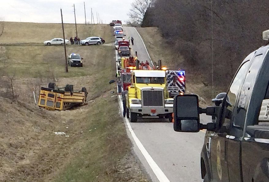 A tow truck, fire truck and emergency response personnel work on the scene of an overturned school bus near the rural northeast town of Ewing, Mo., Tuesday, April 1, 2014. Authorities say nearly two dozen students were injured in the accident. (AP Photo/Quincy Herald Whig/Steve Bohnstedt)
