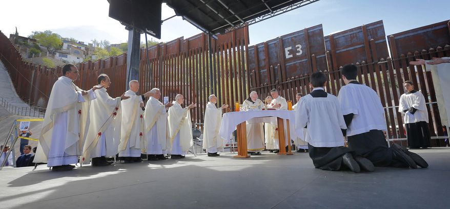 Boston Archdiocese Cardinal Sean O'Malley, center at table, leads mass, Tuesday, April 1, 2014, along the international border wall in Nogales, Ariz. O'Malley and a delegation of Roman Catholic leaders who serve along the U.S./Mexico were visiting the border town to bring awareness to immigration reform and to remember those who have died trying to cross the border in years past. (AP Photo/Matt York)