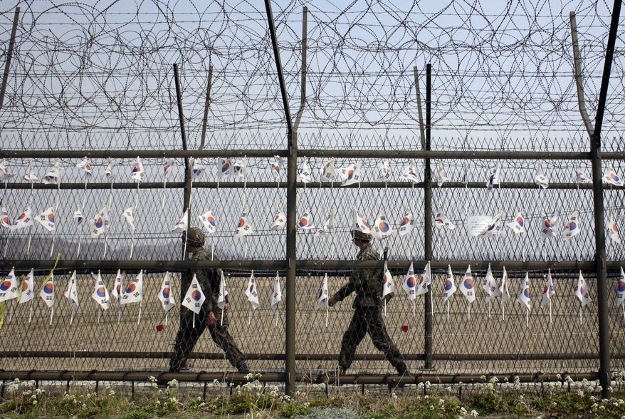 South Korean soldiers patrol through the military wire fences with hanging national flags at the Imjingak Pavilion near the border village of Panmunjom, which has separated the two Koreas since the Korean War, in Paju, north of Seoul, Tuesday, April 1, 2014. North and South Korea fired hundreds of artillery shells into each other's waters Monday in a flare-up of animosity that forced residents of five front-line South Korean islands to evacuate to shelters for several hours, South Korean officials said. (AP Photo/Lee Jin-man)