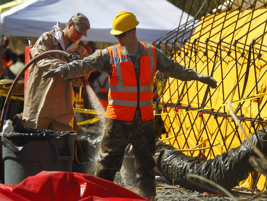Workers go through the first stage of the decontamination process after coming off the site of a fatal mudslide near Oso, Wash., on Tuesday, April 1, 2014. The March 22 mudslide destroyed a rural mountainside community northeast of Seattle. (AP Photo/The Herald, Mark Mulligan) MANDATORY CREDIT.