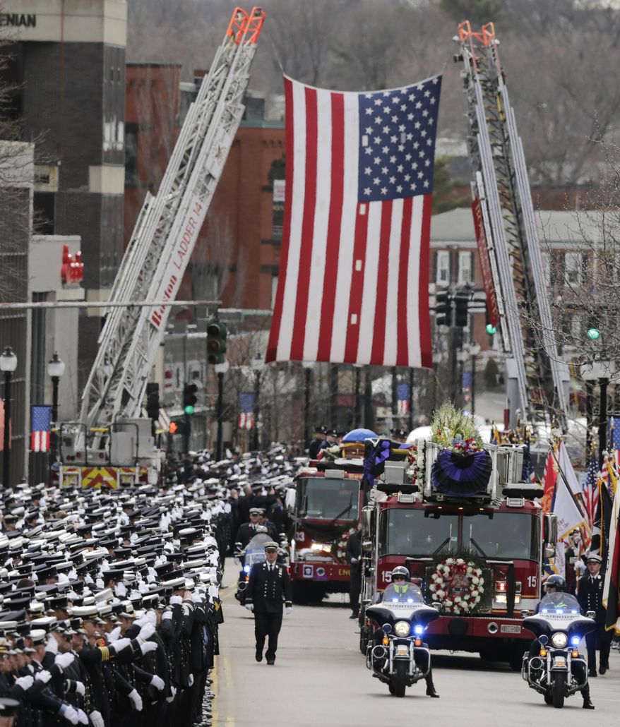 Firefighters salute as the funeral procession for Boston Fire Lt. Edward Walsh rolls under a flag spanning Main Street enroute to St. Patrick's Church in Watertown, Mass., Wednesday, April 2, 2014. Walsh and his colleague Michael Kennedy died after being trapped while battling a nine-alarm apartment fire in Boston on March 26. (AP Photo/Charles Krupa)