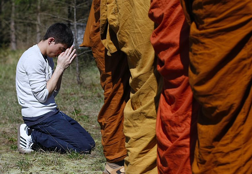 Adisorn Gronski, left, prays while monks from the Atammayatarama Buddhist Monastery in Woodinville chant for victims of the deadly mudslide in Oso, Wash., Tuesday, April 1, 2014, near a road block in Oso. The March 22 mudslide destroyed the rural mountainside community northeast of Seattle. (AP Photo/The Herald, Sofia Jaramillo) MANDATORY CREDIT.