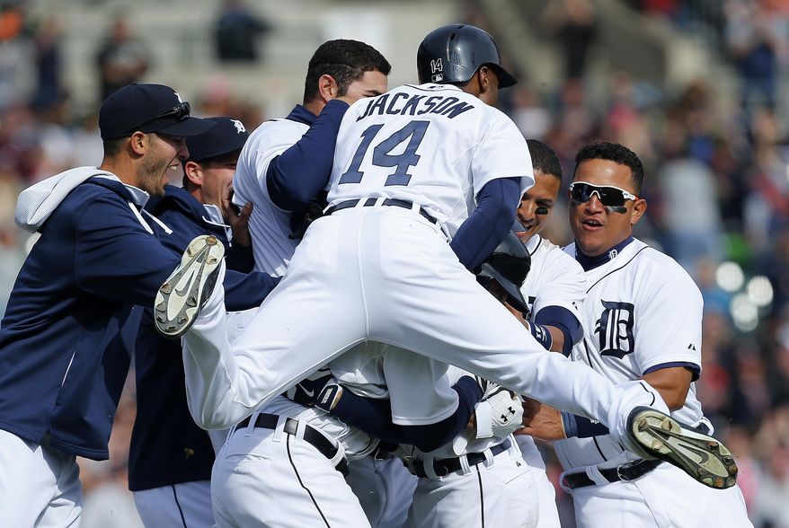 Detroit Tigers center fielder Austin Jackson (14) piles on teammate Ian Kinsler as the team celebrates Kinsler's hitting a walkoff-single against the Kansas City Royals in the 10th inning of a baseball game in Detroit, Wednesday, April 2, 2014. Detroit won 2-1. (AP Photo/Paul Sancya)