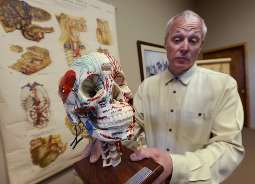 In this April 1, 2014 photo, Dr. Tom Pliura, head of the McLean County Medical Society, holds an anatomical skull in his office in LeRoy, Ill. A group of doctors in central Illinois is opening a cadaver dissection lab for high school students to give young people a head-start on future medical careers. The McLean County Medical Society is sponsoring the lab. It will be open to select students from advanced courses in subjects like anatomy and biology. (AP Photo/The Pantagraph, Steve Smedley)