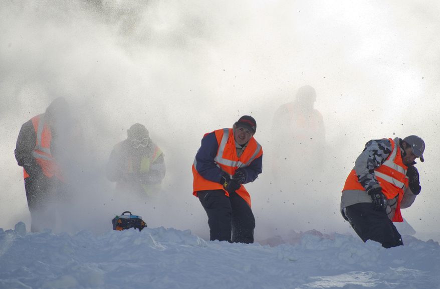 In this photo taken on March 22, 2014, hill helpers duck and cover as another sled spews snow, ice and maybe a little rock down the course at the World Championship Snowmobile Hill Climb in Jackson Hole,Wyo . The volunteers throw themselves into harms way to save riders and their machines from tumbling down the mountain. (AP Photo/Jackson Hole News & Guide, Price Chambers)