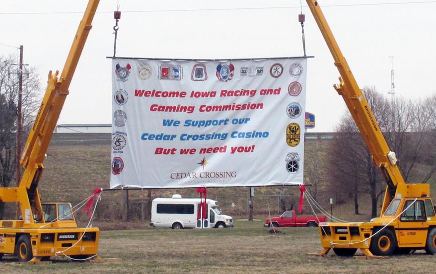 Cranes hold up a banner with a message to the Iowa Racing and Gaming Commission at the site of a proposed casino in Cedar Rapids, Iowa on Thursday, April 3, 2014. The commission held a public hearing Thursday as it considers whether to approve the project, which is opposed by some existing casinos. (AP Photo/Ryan J. Foley)