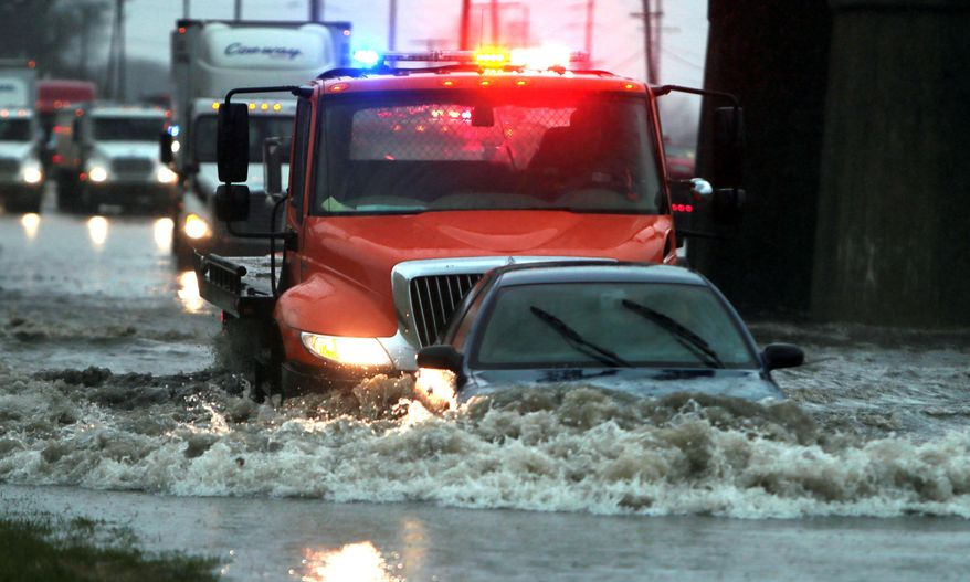 A wrecker pushes a driver to safety as she steers her way out from a flooded patch of road, Wednesday, April 2, 2014, in St. Louis. High waters stranded three vehicles. No one was injured. (AP Photo/St. Louis Post-Dispatch, Laurie Skrivan) EDWARDSVILLE INTELLIGENCER OUT; THE ALTON TELEGRAPH OUT.