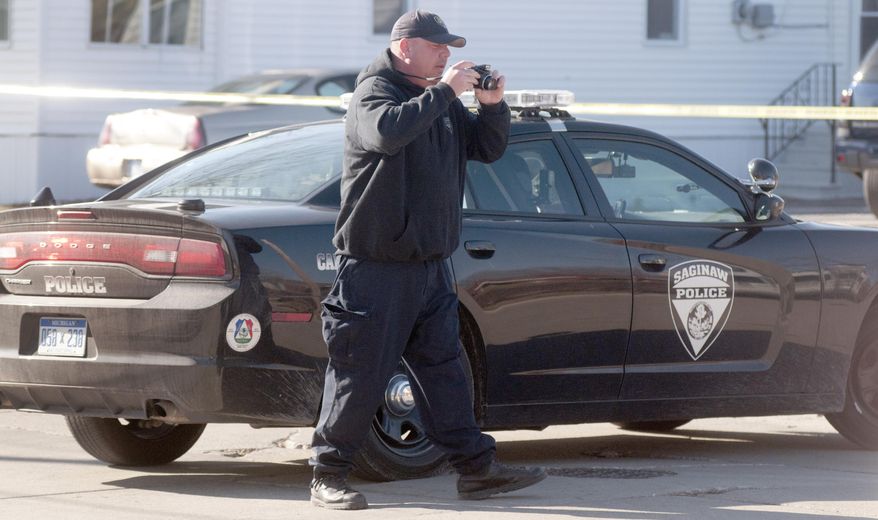 A Saginaw Police officer takes photographs of the scene while investigating a fatal shooting on Saginaw's northeast side, Wednesday, April 2, 2014. A male was confirmed dead behind the house. Hundreds of people took to the streets of Saginaw as part of an anti-violence effort that began the same day as the fatal shooting in the city. Police Chief Brian Lipe told the crowd that officers were investigating the city's first gun-related homicide of 2014. That announcement brought boos from the crowd, which included police, firefighters, community leaders and youth group members. (AP Photo/The Saginaw News, Jeff Schrier) ALL LOCAL TV OUT; LOCAL TV INTERNET OUT
