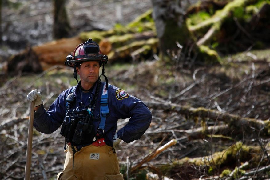 Capt. Jeff Zonrnes, of the Monroe Fire Department, looks on in the debris field, Wednesday, April 2, 2014, as volunteers worked to clear more of the mudslide area in Oso, Wash. A deadly mudslide in March killed more than two dozen people. (AP Photo/The Herald, Genna Martin)