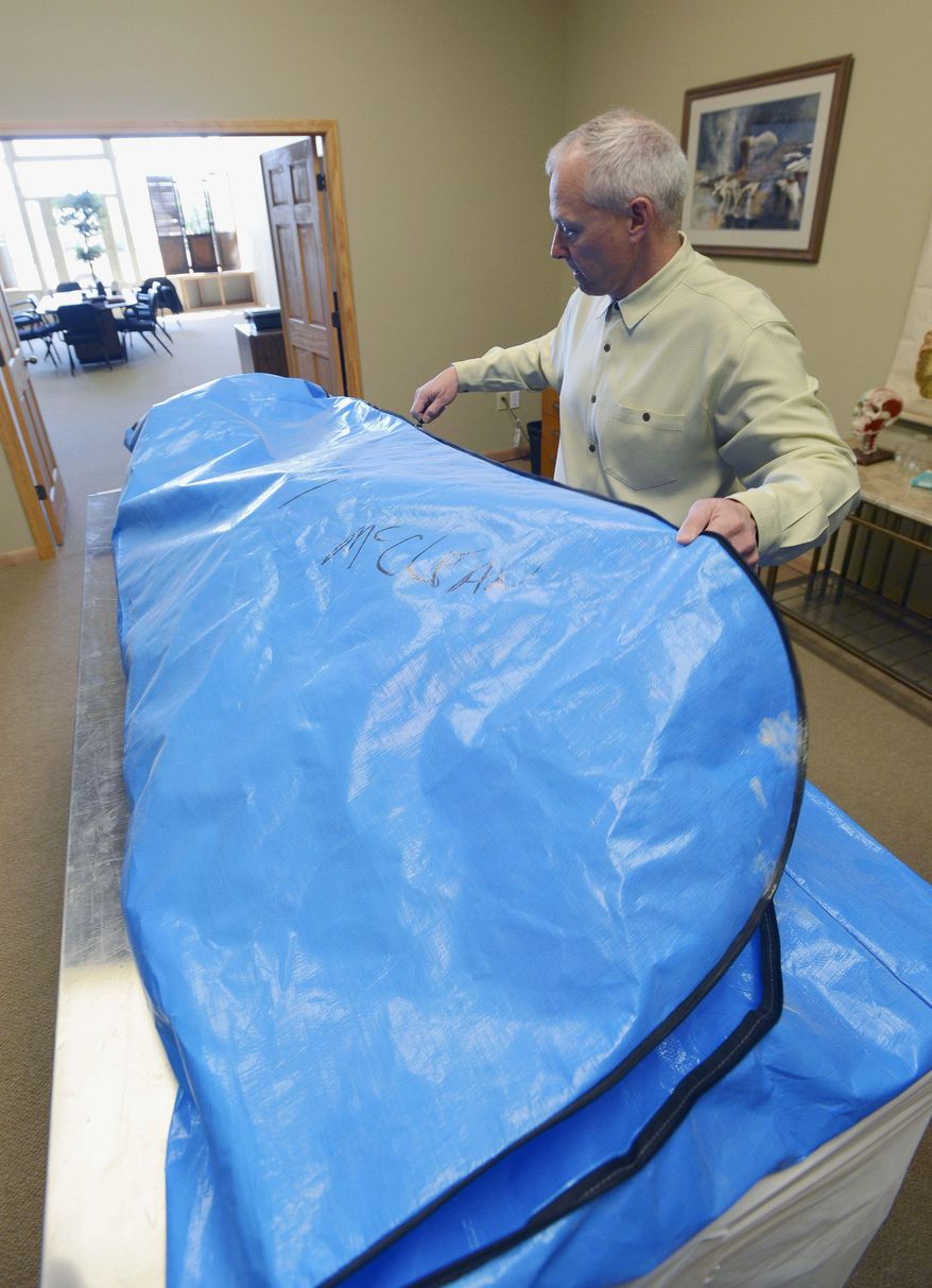 In this April 1, 2014 photo, Dr. Tom Pliura closes a body bag on a recently acquired cadaver in his office in LeRoy, Ill. Pliura is head of the McLean County Medical Society which is sponsoring a cadaver dissection lab for high school students to give young people a head-start on future medical careers. Pliura hopes to begin after-school dissection labs on April 10. (AP Photo/The Pantagraph, Steve Smedley)