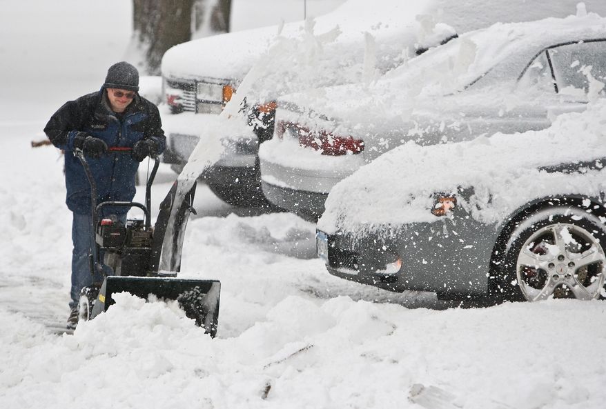 Keith Swanson clears snow from his Pine Island, Minn., driveway and walk on Friday, April 4, 2014. The National Weather Service has issued a winter storm warning for eastern and southern Minnesota until mid-morning. Another band of snow is expected to bring 1 to 2 inches of additional snow in the Twin Cities before it diminishes later Friday morning. (AP Photo/The Rochester Post-Bulletin, Jerry Olson)