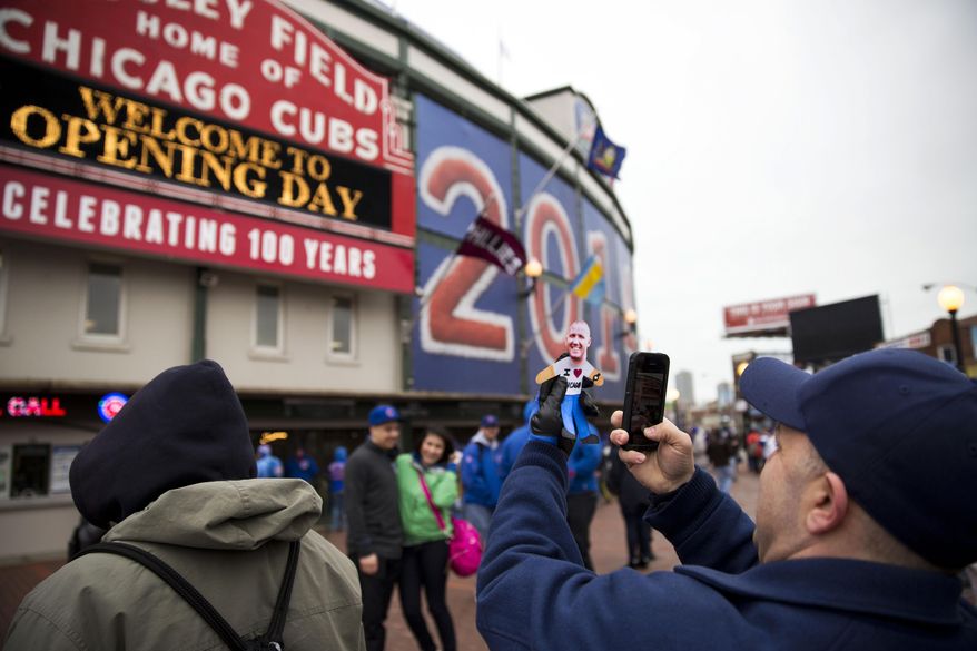 Mark Maroon, of Aurora, Ill., takes a picture of a cutout of his brother-in-law before the Chicago Cubs home opener against the Philadelphia Phillies on Friday, April 4, 2014, in Chicago. (AP Photo/Andrew A. Nelles)