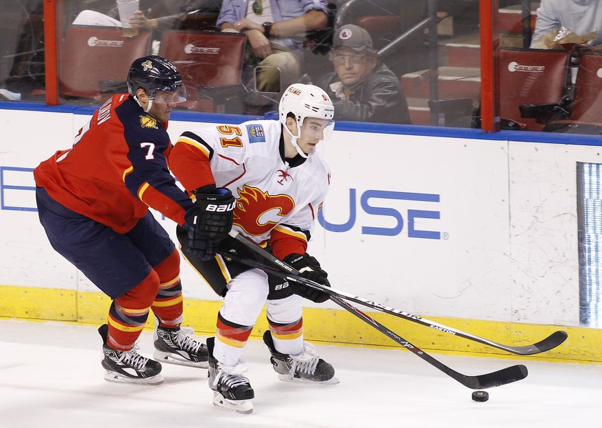 Florida Panthers defenseman Dmitry Kulikov (7) and Calgary Flames left wing Ken Agostino (51) fight for the puck during the first period of an NHL hockey game in Sunrise, Fla., Friday, April 4, 2014. (AP Photo/Terry Renna)