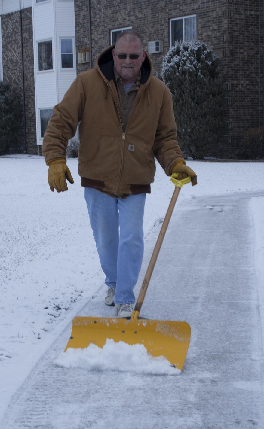 Ken Fischer removes snow from a sidewalk at Hill Street Place in Marshall, Minn., on Friday, April 4, 2014. The National Weather Service has issued a winter storm warning for eastern and southern Minnesota until mid-morning. Another band of snow is expected to bring 1 to 2 inches of additional snow in the Twin Cities before it diminishes later Friday morning. (AP Photo/The Independent, Anna Haecherl-Smith)