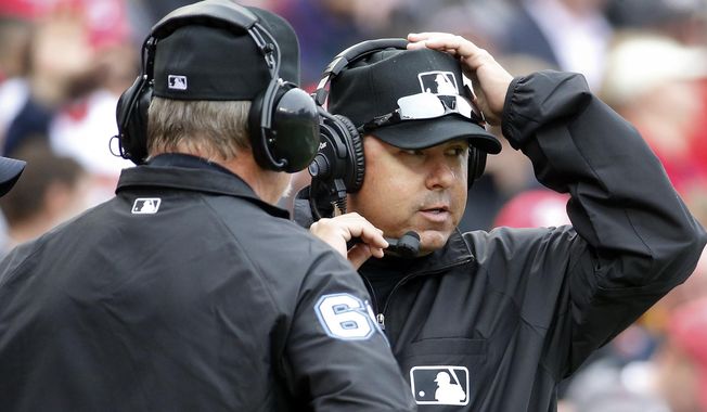 Umpires Jim Joyce, left, and Doug Eddings talk on head phones as they review a call during the fifth inning of a baseball home opener between the Washington Nationals and Atlanta Braves at Nationals Park Friday, April 4, 2014, in Washington. Ian Desmond&#x27;s inside-the-park homer was overturned on replay review and changed to a ground-rule double.(AP Photo/Alex Brandon)