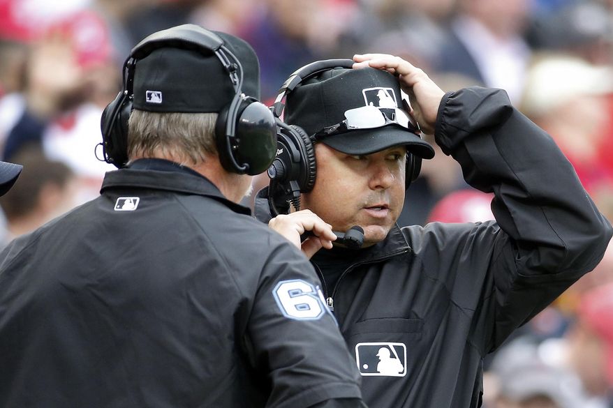 Umpires Jim Joyce, left, and Doug Eddings talk on head phones as they review a call during the fifth inning of a baseball home opener between the Washington Nationals and Atlanta Braves at Nationals Park Friday, April 4, 2014, in Washington. Ian Desmond's inside-the-park homer was overturned on replay review and changed to a ground-rule double.(AP Photo/Alex Brandon)