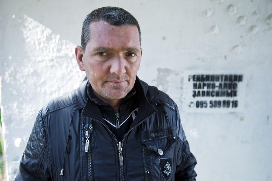 In this photo taken Tuesday, April 1, 2014, Sergei, a patient of treatment for drug addiction, poses at a bus stop with an advert reading "Rehabilitation of drug and alcohol addicts" in Sevastopol, Crimea. Across the Black Sea peninsula, some 800 heroin addicts and other needle-drug users take part in methadone programs, seen as an important part of efforts to curb HIV infections by taking the patients away from hypodermic needles that can spread the AIDS-causing virus. After Russia's annexation of Crimea methadone was banned. The ban could undermine years of efforts to reduce the spread of AIDS in Crimea. (AP Photo/Pavel Golovkin)