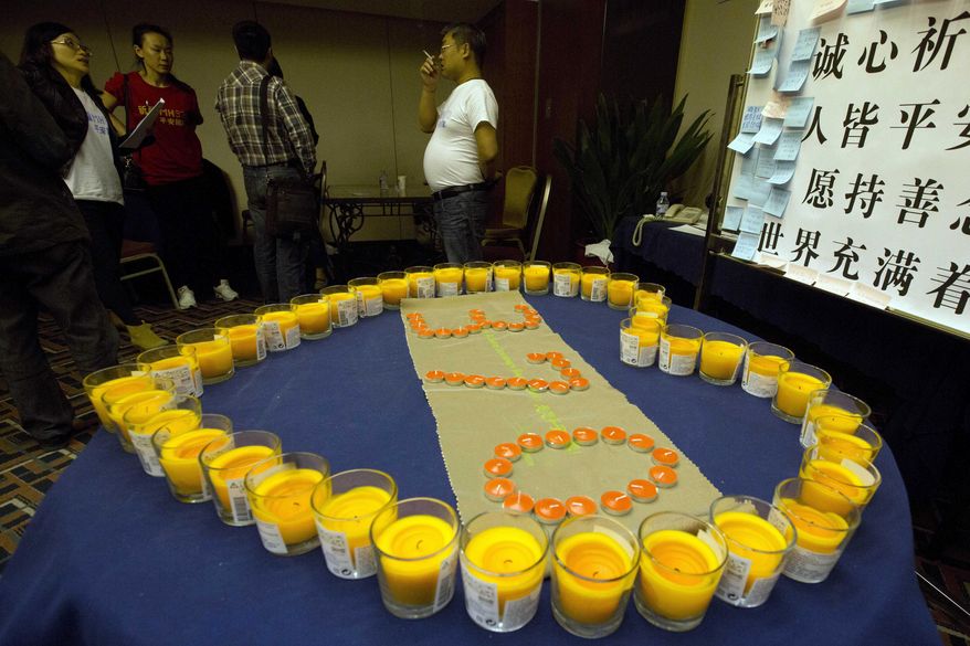 Relatives of Chinese passengers onboard the Malaysia Airlines MH370 stand near candles arranged as a memorial in a prayer room in Beijing, China, Thursday, April 3, 2014. No trace of the Boeing 777 has been found nearly a month after it vanished in the early hours of March 8 on a flight from Kuala Lumpur to Beijing with 239 people on board. (AP Photo/Ng Han Guan)