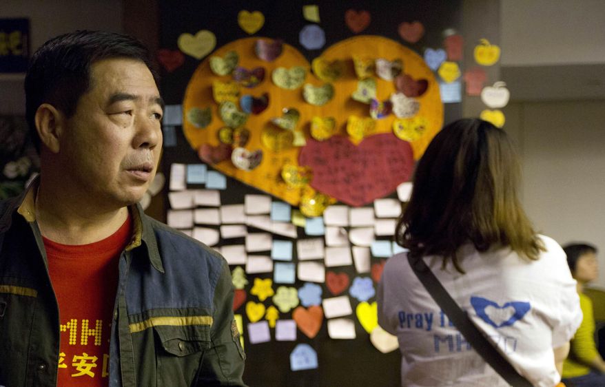 Relatives of Chinese passengers onboard the Malaysia Airlines MH370 stand near messages of well wishes, pasted onto the wall, in a prayer room in Beijing, China, Thursday, April 3, 2014. No trace of the Boeing 777 has been found nearly a month after it vanished in the early hours of March 8 on a flight from Kuala Lumpur to Beijing with 239 people on board. (AP Photo/Ng Han Guan)