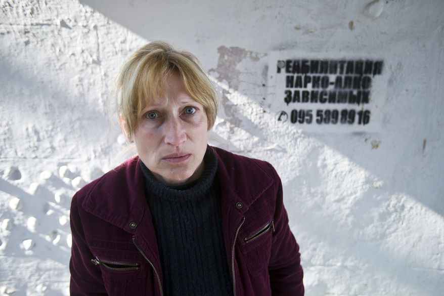 In this photo taken Tuesday, April 1, 2014, Svetlana Starikova, a patient of treatment for drug addiction, poses at a bus stop with an advert reading "Rehabilitation of drug and alcohol addicts" in Sevastopol, Crimea. Across the Black Sea peninsula, some 800 heroin addicts and other needle-drug users take part in methadone programs, seen as an important part of efforts to curb HIV infections by taking the patients away from hypodermic needles that can spread the AIDS-causing virus. After Russia's annexation of Crimea methadone was banned. The ban could undermine years of efforts to reduce the spread of AIDS in Crimea. (AP Photo/Pavel Golovkin)