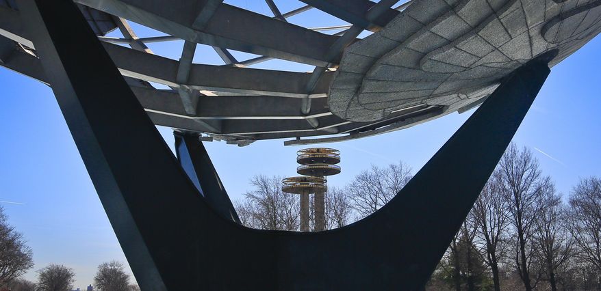 A space-age tower, center, is viewed between the support pillars of a giant metal globe called the Unisphere, structures remaining from the 1964 World's Fair, on Tuesday April 1, 2014 in the Queens borough of New York. As this month’s 50th anniversary of the 1964 New York World’s Fair approaches, a debate has emerged about what to do with some of the fair’s most famous structures. The towers topped by flying-saucer-like platforms, and a pavilion of pillars once called the “Tent of Tomorrow,” still sit as abandoned relics in the middle of Queens' Flushing Meadows Corona Park. (AP Photo/Bebeto Matthews)