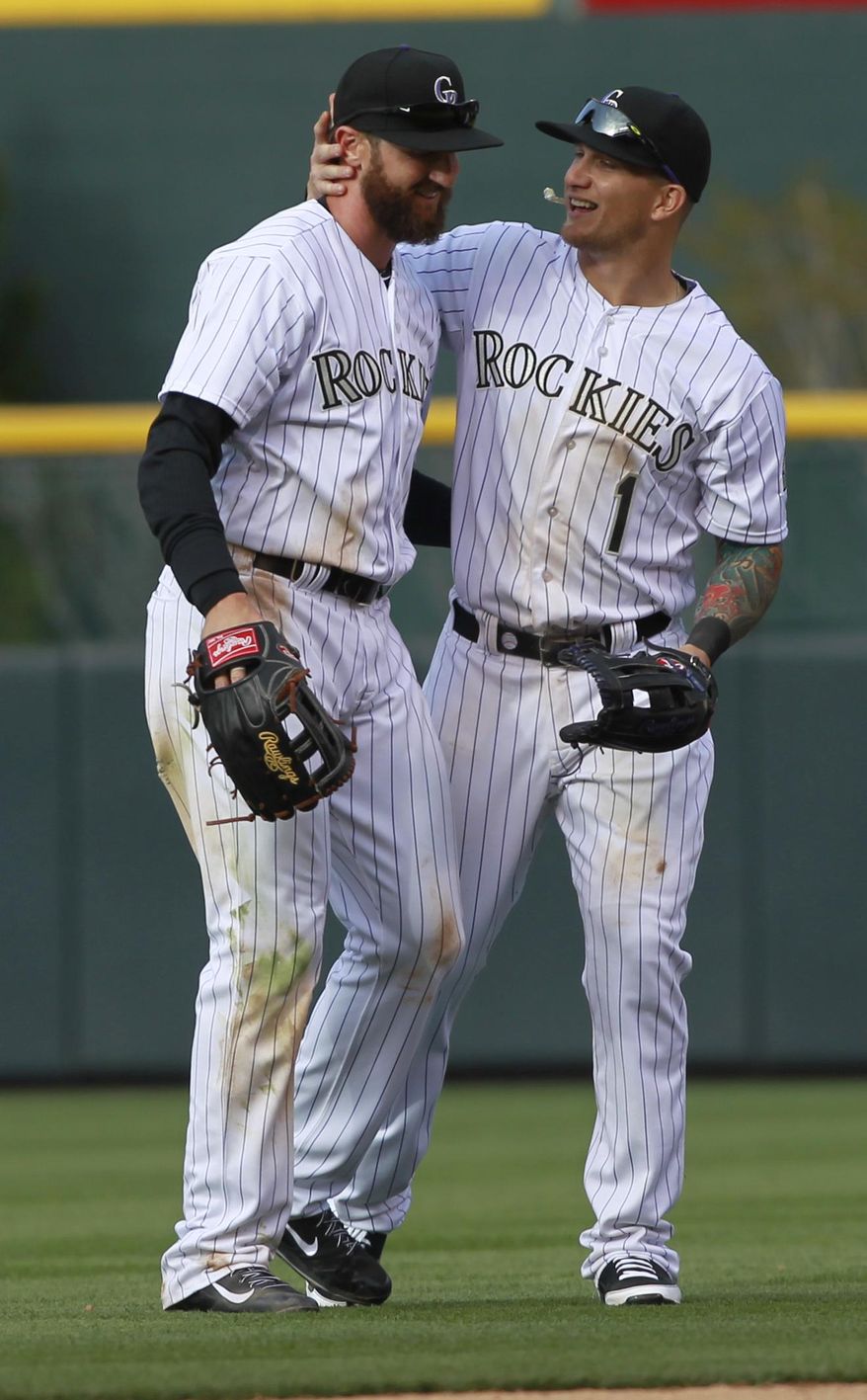 Colorado Rockies left fielder Charlie Blackmon, left, is congratulated by teammate Brandon Barnes after Blackmon led the Rockies to a 12-2 victory over the Arizona Diamondbacks in a baseball game in Denver on Friday, April 4, 2014. Blackmon tied a team record with six hits set by Andres Galarraga on July 3, 1995, against the Houston Astros. (AP Photo/David Zalubowski)