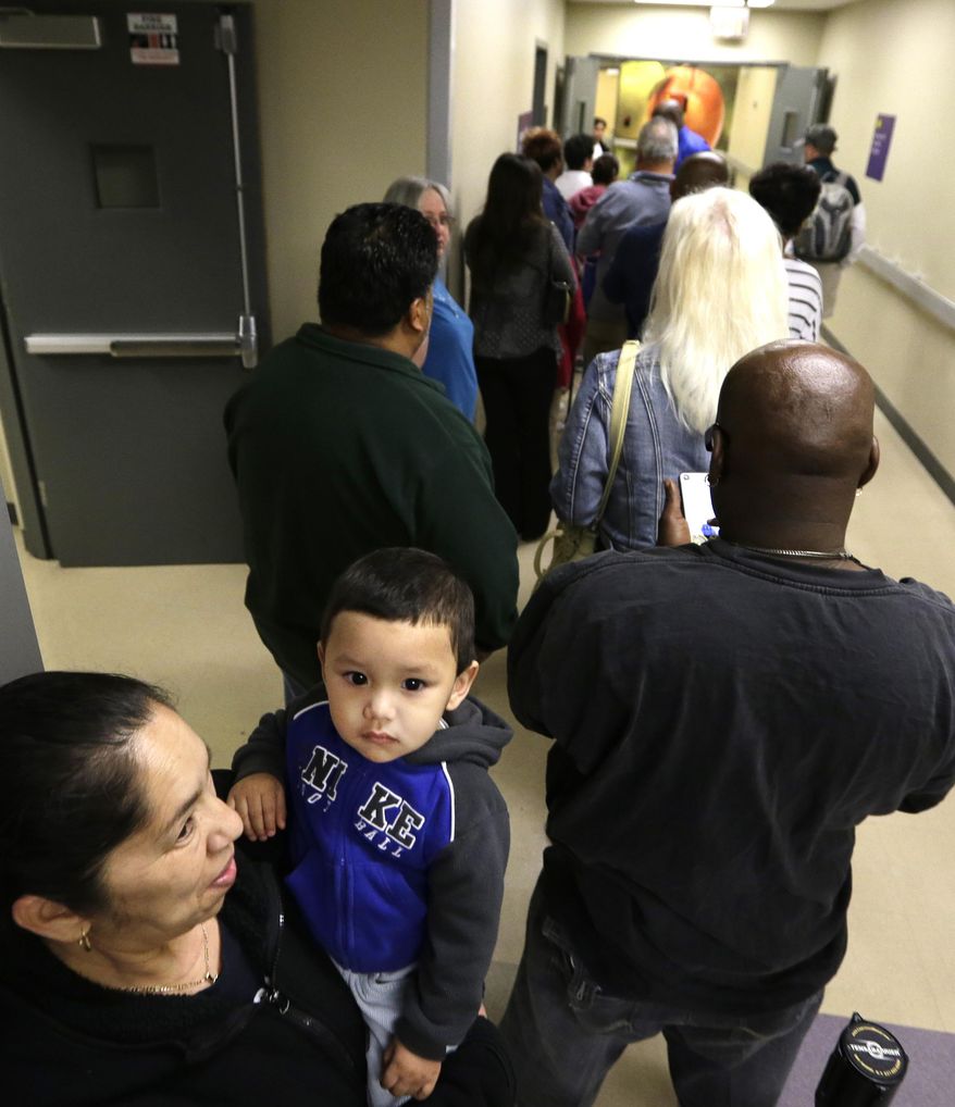 FILE - This March 31, 2014, file photo shows Susana Martinez, left, holding her one-year-old grandson Giovanni Gonzales, wait in line with others waiting to sign up for health care insurance at the business office of Parkland Hospital in Dallas. Seven million sign-ups proves there's an appetite in the country for President Barack Obama's health care law, but it doesn't guarantee success for America's newest social program. The top priorities for the administration now guaranteeing that premiums remain affordable next year, making enrollment simpler, and improving subpar customer service. Republican opponents also face some tough questions: as millions of people get insurance, how long can the GOP's repeal strategy remain a viable political option? (AP Photo/LM Otero, File)