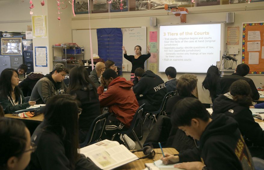 In this March 3, 2014 photo, Valerie Ziegler, rear, teaches during 12th grade government class at Abraham Lincoln High School in San Francisco. To be eligible for California’s public universities, high school students must complete 15 classes with a grade of C or better, including two years of foreign language, lab science, intermediate algebra, and visual or performing arts. Yet fewer than four of 10 do, fueling worries the state is facing a shortage of college-educated workers when the earning power a bachelor’s degree has never been higher. (AP Photo/Jeff Chiu)