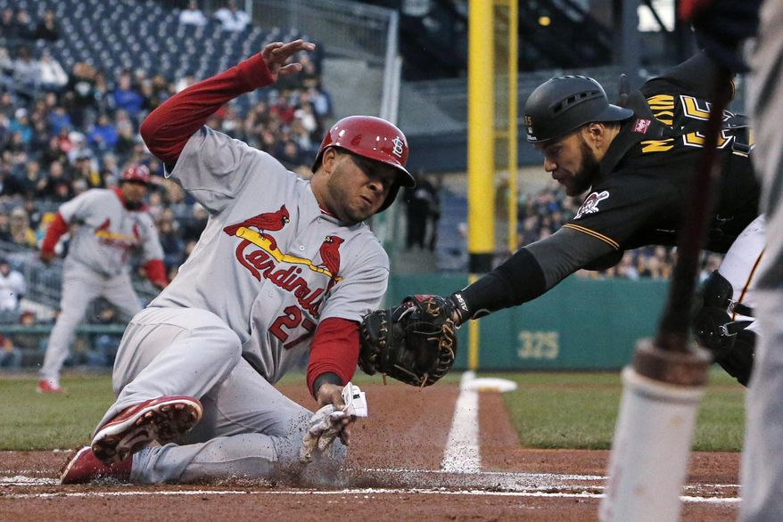 St. Louis Cardinals' Jhonny Peralta (27) slides safely around the attempted tag by Pittsburgh Pirates catcher Russell Martin during the first inning of a baseball game in Pittsburgh on Saturday, April 5, 2014. Peralta scored from third on a sacrifice fly by Allen Craig. (AP Photo/Gene J.Puskar)