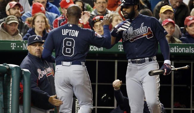Atlanta Braves&#x27; Justin Upton (8) celebrates after scoring, with manager Fredi Gonzalez, left, and Jason Heyward during the fourth inning of a baseball game against the Washington Nationals at Nationals Park Saturday, April 5, 2014, in Washington. Upton scored on a throwing error by Nationals third baseman Ryan Zimmerman. (AP Photo/Alex Brandon)