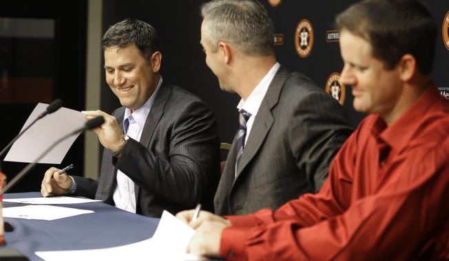 Former Houston Astros players Lance Berkman, left, and Roy Oswalt, right, sign one-day service contracts as club president Reid Ryan looks on during a news conference before a baseball game against the Los Angeles Angels, Saturday, April 5, 2014, in Houston. Berkman and Oswalt signed the contracts so they could retire as Astros. (AP Photo/Pat Sullivan)