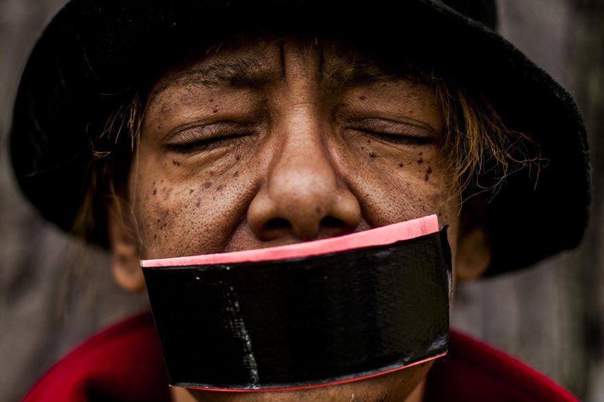 Flint resident Claire McClinton stands silently with her eyes closed and tape over her mouth during a silent protest against the change to limit public speaking to three minutes during Flint city council meetings on Friday, April 4, 2014 at Flint City Hall. Emergency Manager Darnell Earley made the change April 1, also moving the public speaking portion at the end of the meetings. "You've already taken our democracy away," she said. "Now, our voices are silenced." (AP Photo/The Flint Journal, Jake May)