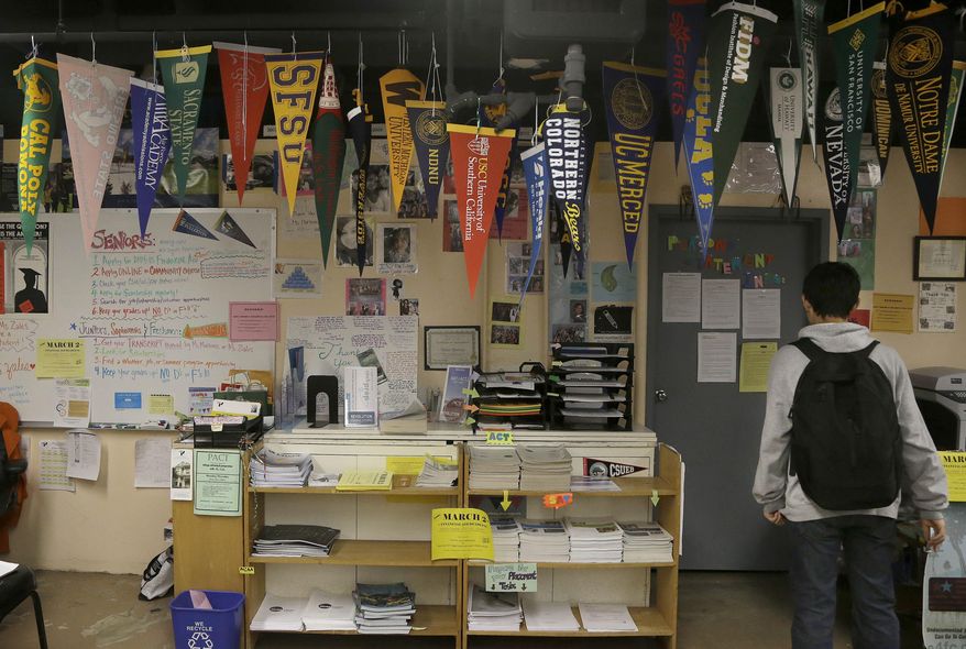 In this March 3, 2014 photo, a student at walks under collegiate pennants in the college and career center at Abraham Lincoln High School in San Francisco. To be eligible for California’s public universities, high school students must complete 15 classes with a grade of C or better, including two years of foreign language, lab science, intermediate algebra, and visual or performing arts. Yet fewer than four of 10 do, fueling worries the state is facing a shortage of college-educated workers when the earning power a bachelor’s degree has never been higher. (AP Photo/Jeff Chiu)