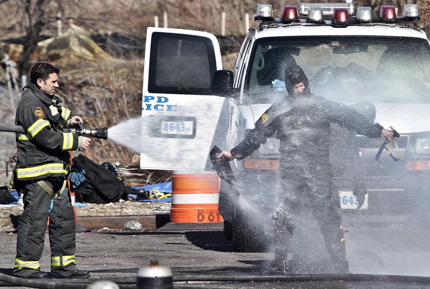 A police diver, fearful of contamination, is sprayed with water from a firefighter, after diving the Steinway Creek to recover a 2009 Honda Accord on Saturday April 5, 2014 in New York. The driver of the car drove off a dead-end street in a desolate industrial area, flipped over a wooden curb into the East River inlet killing four passengers. The driver escaped serious injury and told officers at the scene in the Astoria section of Queens that the four were trapped in the submerged car. Fire department divers pulled the four victims from the car. Police identified them as 21-year-old Darius Fletcher, 19-year-old Jada Monique Butts, 19-year-old Crystal Gravely and 20-year-old Jaleel Furtado. They were pronounced dead at hospitals. (AP Photo/Bebeto Matthews)