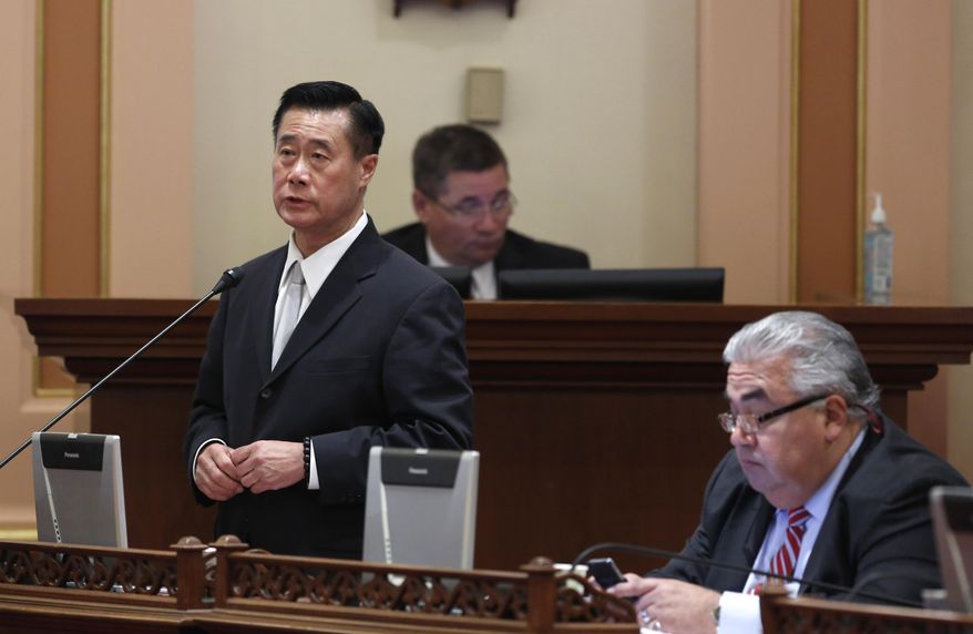FILE -- In this Jan. 28, 2014 file photo, state Sen. Leland Yee, D-San Francisco, left, speaks on a bill, while his seat mate  Sen. Ron Calderon, D-Montebello, works at his desk at the Capitol  in Sacramento, Calif. In the wake the recent indictments of Yee and Calderon on federal corruption charges lawmakers are proposing to strengthen political ethics and reform campaign finance laws.(AP Photo/Rich Pedroncelli, file)