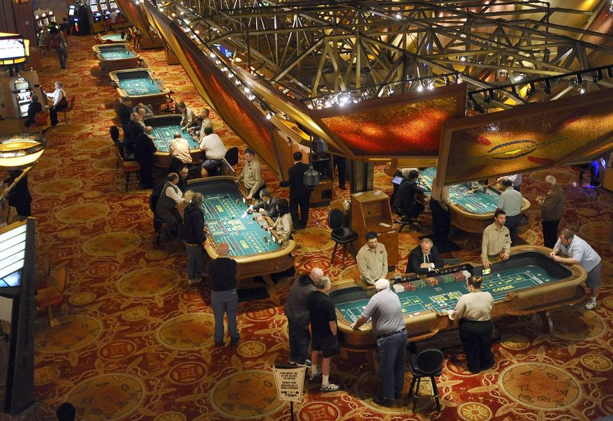 FILE - In this Sept. 18, 2013 file photo, patrons play craps at tables at Mohegan Sun in Uncasville, Conn. A gaming slump is eating into the profits of Mohegan Sun in 2014, but the 2,000 tribal members who draw benefits from the massive casino are not feeling the pinch. The tribe’s gaming company has begun running casinos in Pennsylvania and Atlantic City, and it is pursuing more projects in states including Washington, New York, and Massachusetts. (AP Photo/Jessica Hill, File)