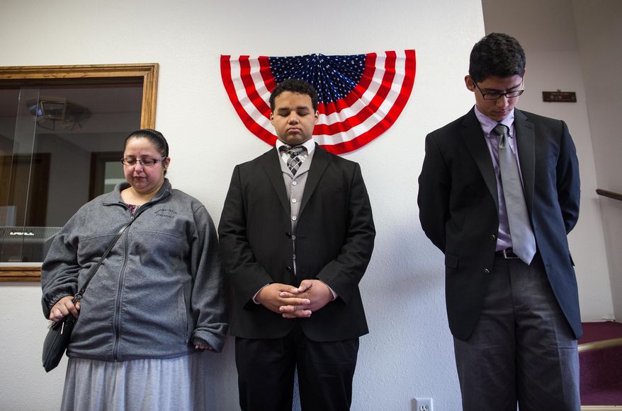 Rebecca Gutierrez, Marcus Bates and Daniel Ramirez pray for the victims and families affected by the Fort Hood shooting during a memorial service at the Tabernacle Baptist Church on Sunday, April 6, 2014, in Killeen, Texas. On April 2, 2014, three people were killed and 16 were wounded when a gunman opened fire before taking his own life at the Fort Hood military base. (AP Photo/ Tamir Kalifa)