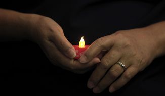 A woman holds an LED candle as she offers prayers during a mass prayer for the missing Malaysia Airlines Flight 370, in Kuala Lumpur, Malaysia, Sunday, April 6, 2014. The head of the multinational search for the missing Malaysia airlines jet said that electronic pulses reportedly picked up by a Chinese ship are an encouraging sign but stresses they are not yet verified. (AP Photo/Lai Seng Sin)