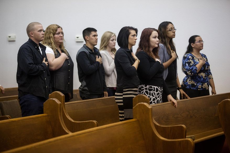 A congregation of military servicemen and civilians listen to the national anthem during a memorial service for the victims and families affected by the Fort Hood Shooting at the Tabernacle Baptist Church on Sunday, April 6, 2014, in Killeen, Texas. On April 2, 2014, three people were killed and 16 were wounded when a gunman opened fire before taking his own life at the Fort Hood military base. (AP Photo/ Tamir Kalifa)