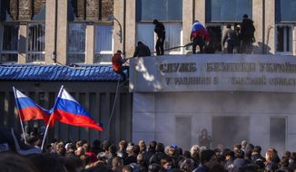 Pro-Russian activists with Russian national flags storm the Ukrainian regional office of the Security Service in Luhansk, Ukraine, Sunday, April 6, 2014. In Luhansk, 30 kilometers (20 miles) west of the Russian border, hundreds of people surrounded the local headquarters of the security service and later scaled the facade to plant a Russian flag on the roof.  (AP Photo/Igor Golovniov)