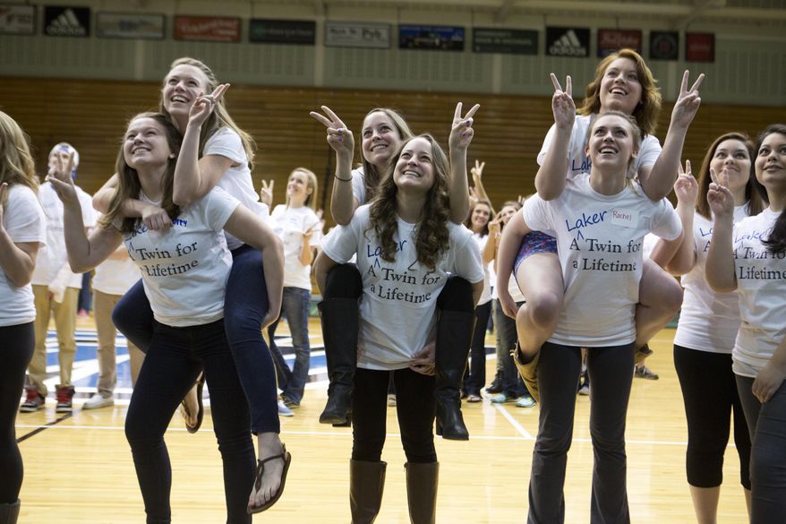 Sets of twins pose for a group photo in the field house at Grand Valley State University in Allendale, Mich. on Sunday, April 6, 2014. The school says there are 101 sets of twins this year, and that 52 sets of currently enrolled twin students showed up. They were joined by 12 sets of twins who are alumni and even a few infant twins. A group photo captured the event at the campus arena. (AP Photo/The Grand Rapids Press, Lauren Petracca) ALL LOCAL TV OUT; LOCAL TV INTERNET OUT