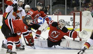 New Jersey Devils goalie Cory Schneider (35) stretches to protect the net as Calgary Flames Curtis Glencross, left, presses between Devil&#39;s &#39; Andy Greene (6) and Anton Volchenkov (28), of Russia, during the first period of an NHL hockey game in Newark, N.J., Monday, April 7, 2014. (AP Photo/Mel Evans)