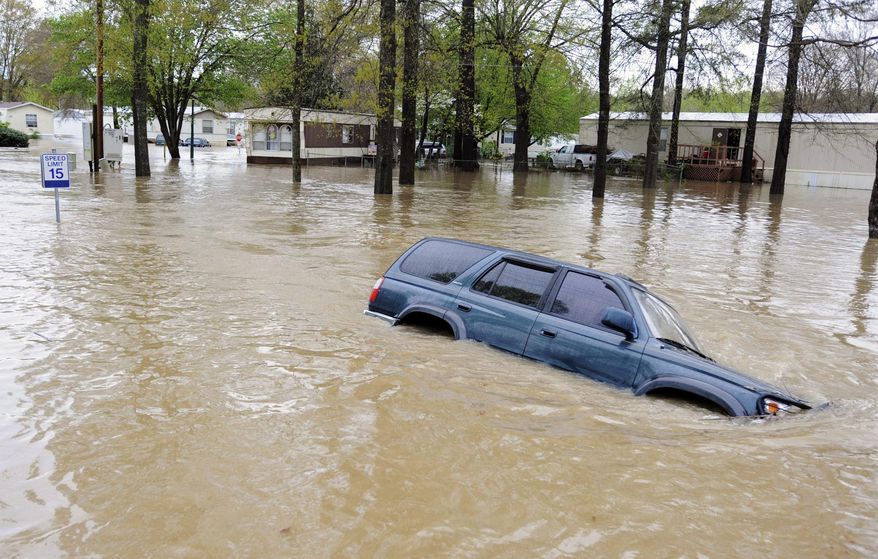 CORRECTS DATE TO APRIL 7 An abandoned vehicle sits submerged by floodwaters on a road in a mobile home park in Pelham, Ala., on Monday, April 7, 2014. Storms dumped torrential rains in central Alabama overnight, causing flooding across the region. (AP Photo/Jay Reeves)