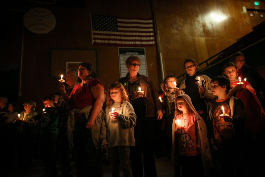 People hold candles during a vigil at the Darrington Community Center on Saturday, April 5, 2014. The vigil was held on the two week anniversary of the Oso mudslide and brought together hundreds of local residents affected by the disaster. (AP Photo/seattlepi.com, Joshua Trujillo)